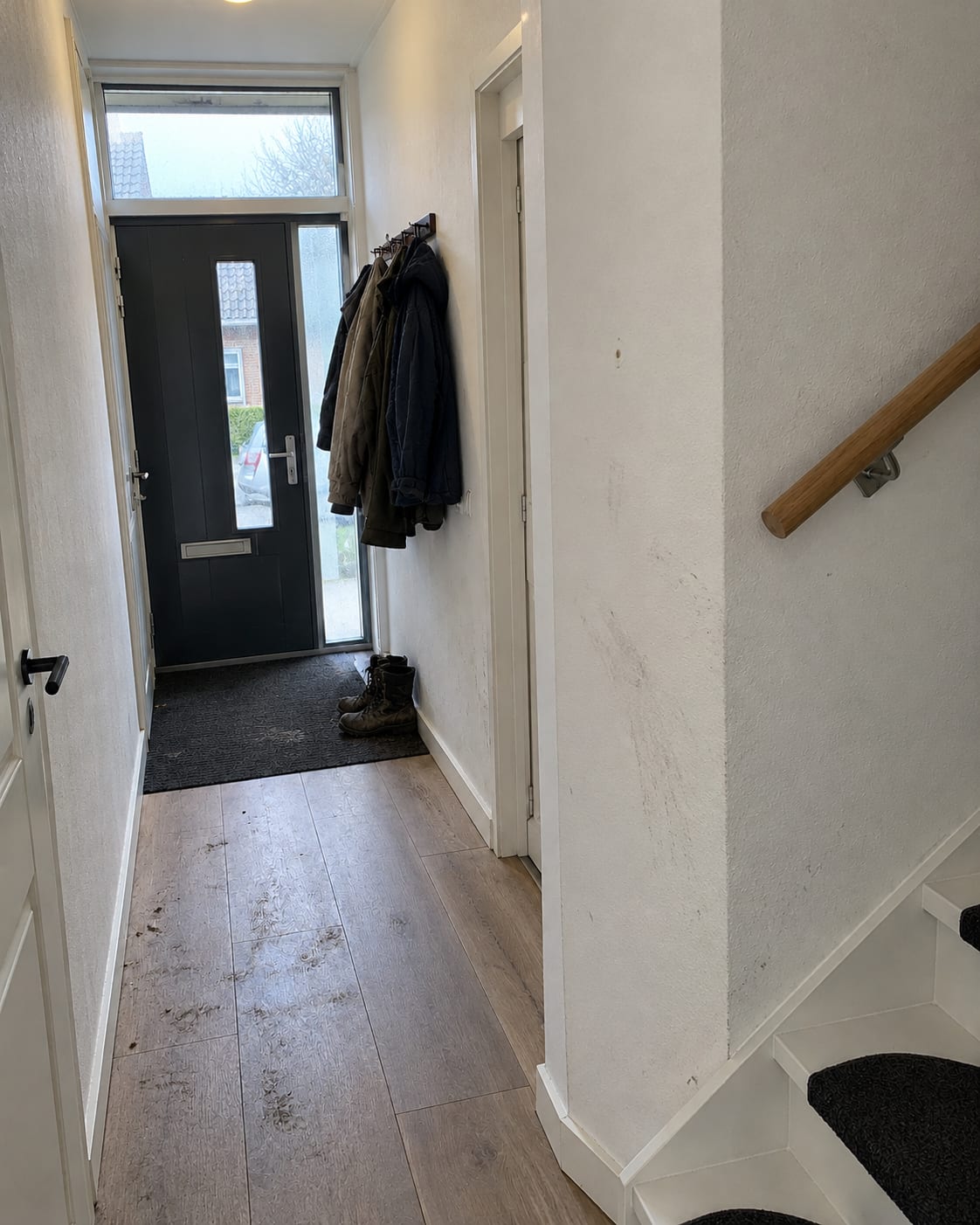 Voor: gangwanden met ruwe sierpleister en verkleuringen langs de trap